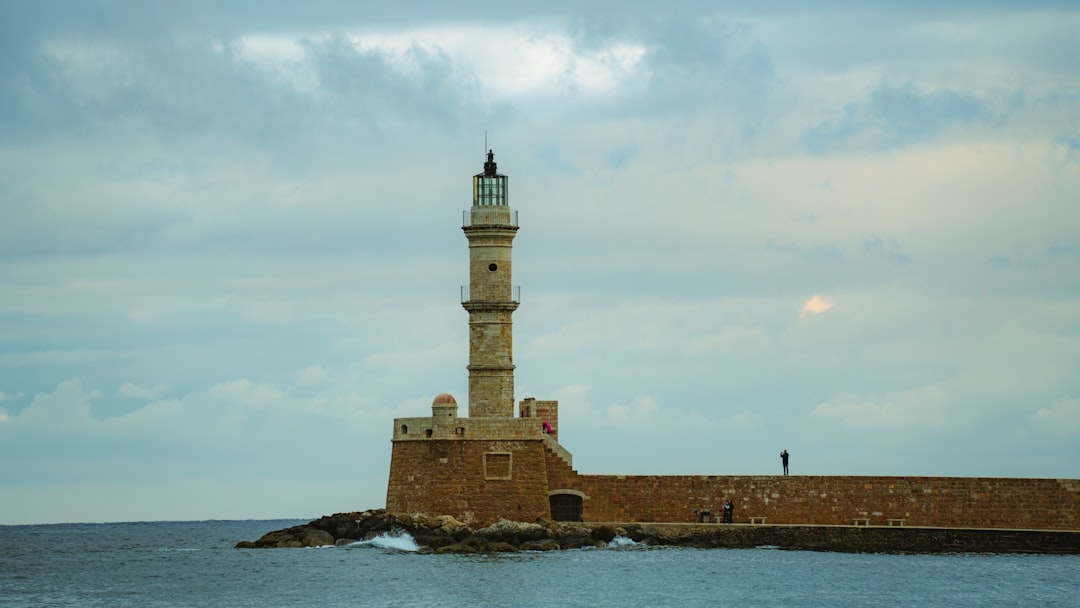 A lighthouse stands on a stone pier by the sea.